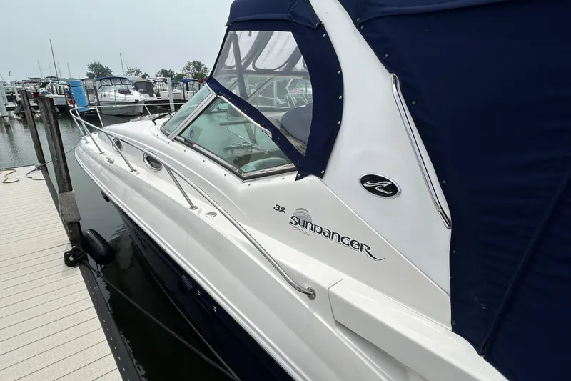 Slide: The Image of 2005 Sea Ray 320 Sundancer docked at marina, featuring sleek design and blue canopy. - 3
