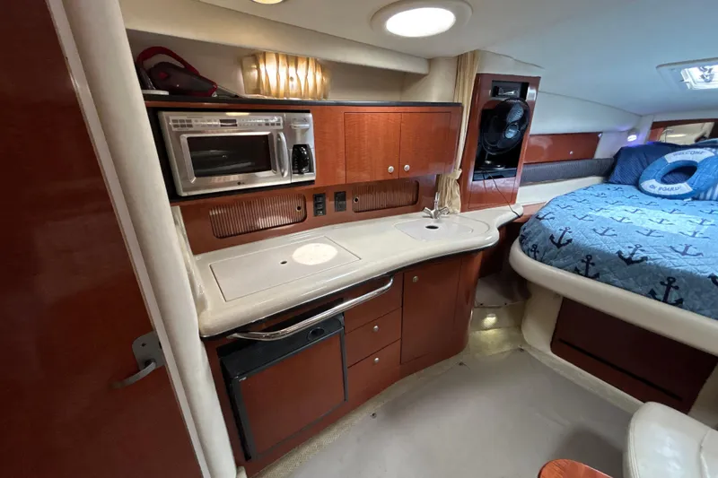 Slide: The Image of 2005 Sea Ray 320 Sundancer interior with kitchenette and cozy sleeping area. - 42