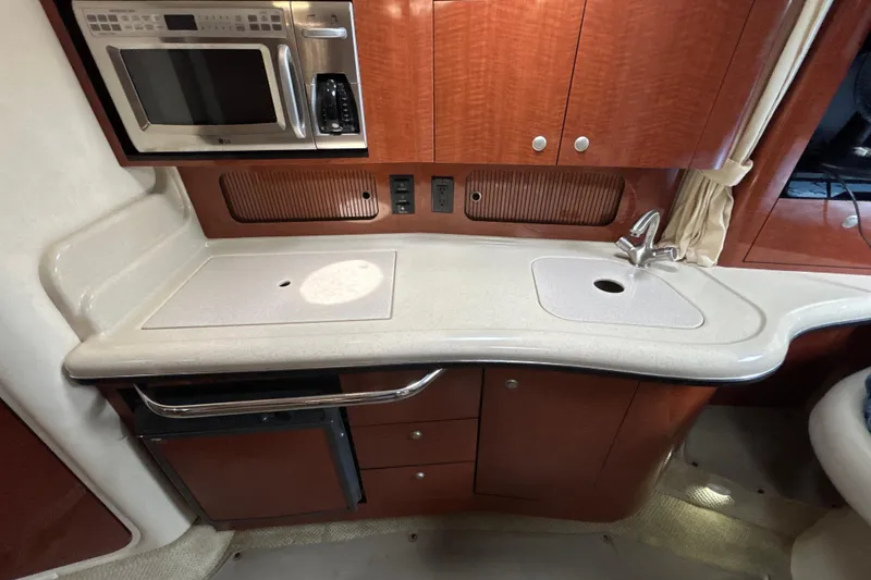 Slide: The Image of 2005 Sea Ray 320 Sundancer galley with microwave, sink, and wooden cabinetry. - 43