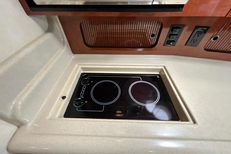 Slide: The Image of 2005 Sea Ray 320 Sundancer kitchen with built-in electric stove and wooden cabinetry. - 46