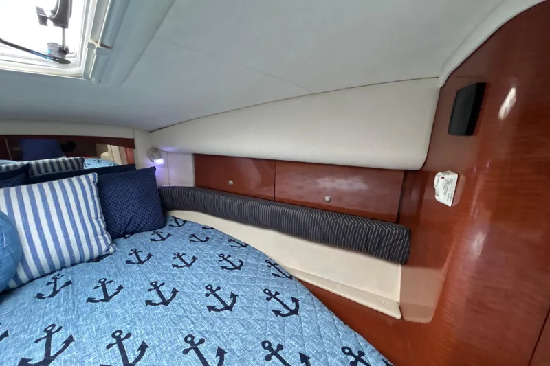Slide: The Image of 2005 Sea Ray 320 Sundancer cabin interior with anchor-themed bedding and striped pillows. - 51