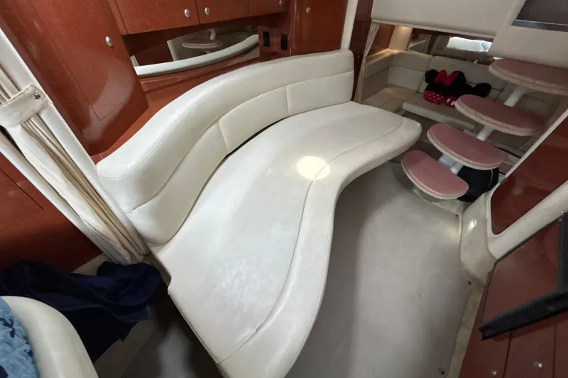 Slide: The Image of 2005 Sea Ray 320 Sundancer interior with curved white seating and wooden cabinetry. - 59