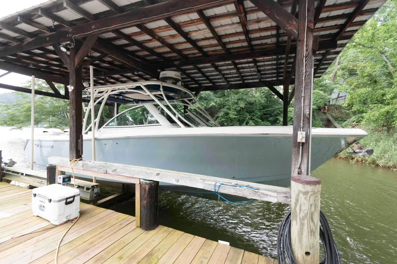 Slide: The Image of 2020 Sailfish 325 DC boat docked under a wooden shelter by the water. - 1