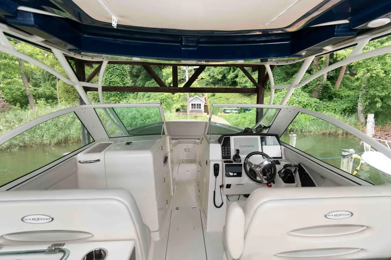 Slide: The Image of 2020 Sailfish 325 DC boat interior with steering console and lush greenery background. - 14