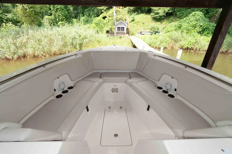 Slide: The Image of 2020 Sailfish 325 DC boat interior with spacious seating and cup holders, docked by lush greenery. - 16