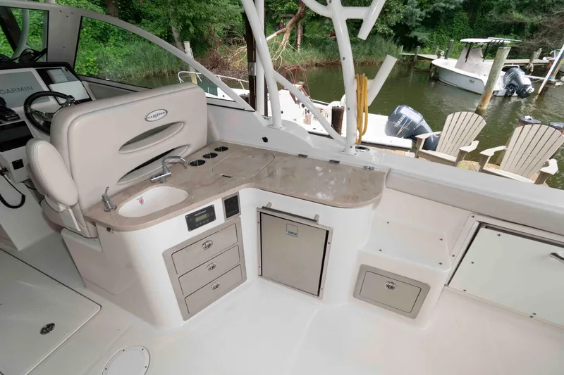 Slide: The Image of 2020 Sailfish 325 DC boat interior with sink, storage, and seating by the water. - 19