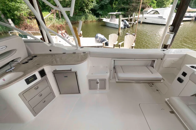 Slide: The Image of 2020 Sailfish 325 DC boat interior with seating, kitchenette, and storage, docked by a serene lake. - 20