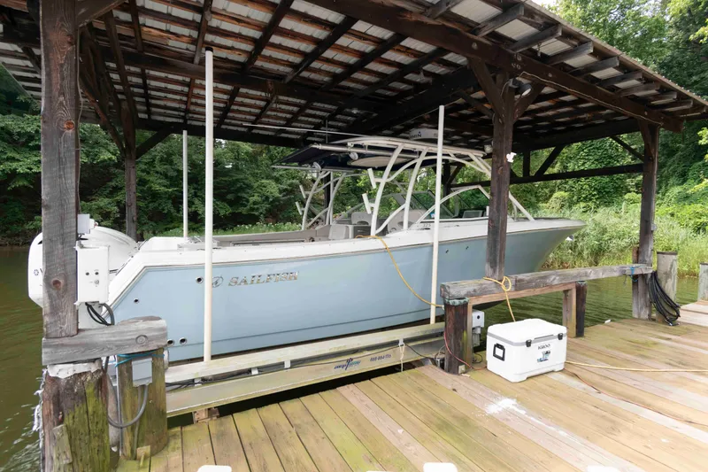 Slide: The Image of 2020 Sailfish 325 DC boat docked under wooden shelter by lush greenery. - 3