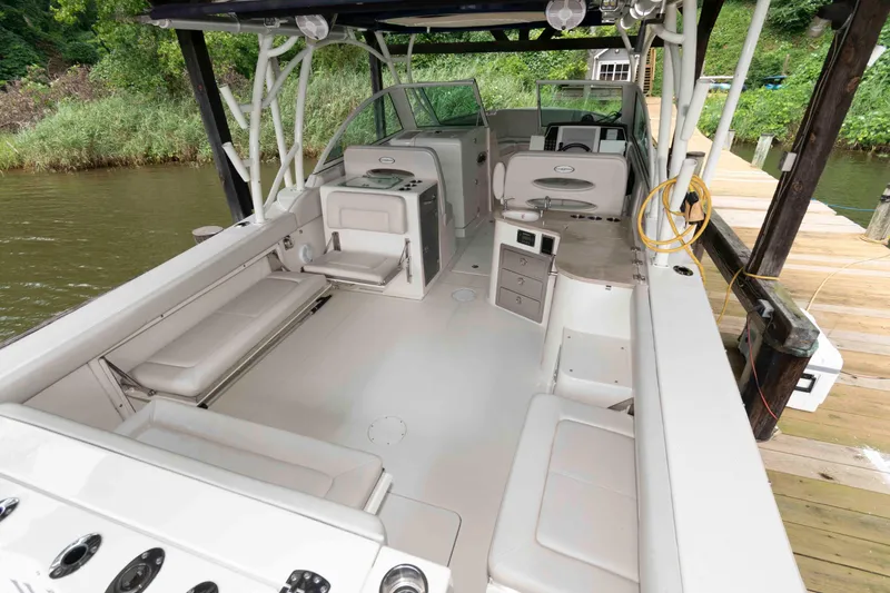 Slide: The Image of 2020 Sailfish 325 DC boat interior with seating and storage, docked by a wooden pier. - 4
