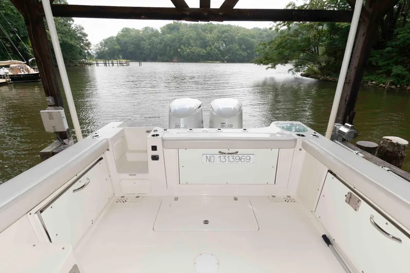 Slide: The Image of 2020 Sailfish 325 DC boat docked on a serene river with lush greenery. - 5
