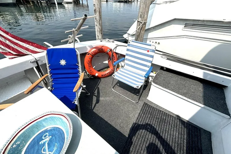 Slide: The Image of 1987 Davidson 48 Sportfish boat deck with chairs, life preserver, and nautical decor. - 14