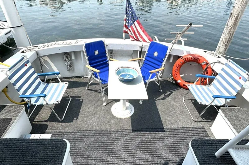 Slide: The Image of 1987 Davidson 48 Sportfish deck with chairs, table, and American flag by the water. - 16