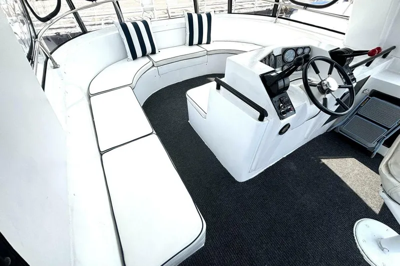 Slide: The Image of 1987 Davidson 48 Sportfish interior with white seating and helm, featuring striped cushions. - 22