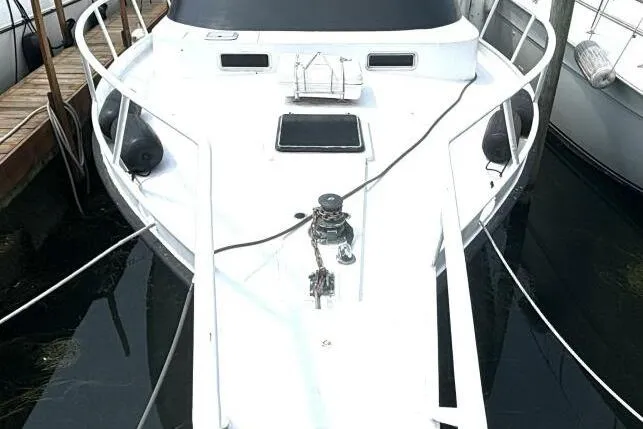Slide: The Image of 1987 Davidson 48 Sportfish boat docked, featuring a sleek white deck and mooring lines. - 3