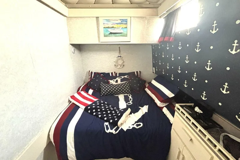 Slide: The Image of Nautical-themed bedroom in 1987 Davidson 48 Sportfish boat with anchor-patterned decor. - 42