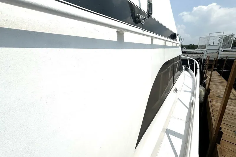 Slide: The Image of 1987 Davidson 48 Sportfish yacht docked, showcasing sleek white exterior and railing. - 9