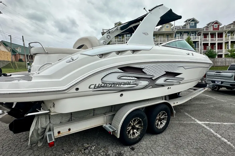 Slide: The Image of 2011 Chaparral 267 SSX boat on trailer, parked in a lot with colorful buildings. - 3