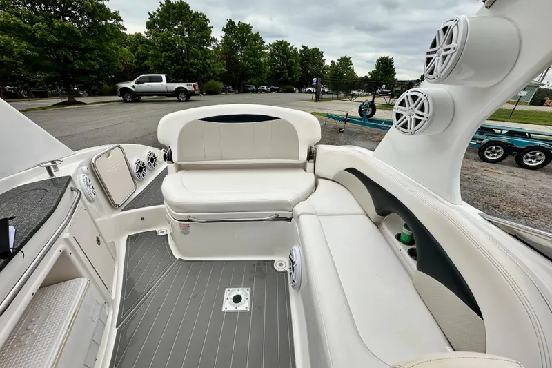 Slide: The Image of 2011 Chaparral 267 SSX boat interior with white seating and speakers, parked outdoors. - 6