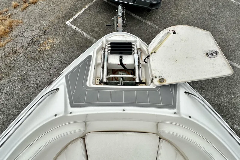 Slide: The Image of 2011 Chaparral 267 SSX boat with open storage compartment, parked on cracked pavement. - 8