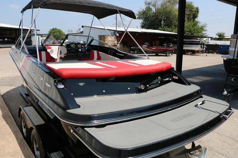 Slide: The Image of 2015 Glastron 205 GTS boat with red and white seating, parked outdoors. - 9