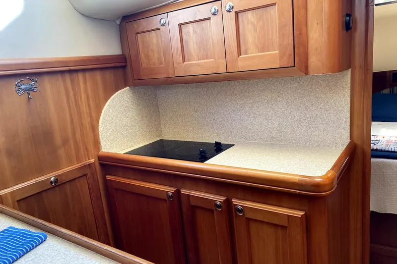 Slide: The Image of 2005 Mainship 34 Trawler kitchen with wooden cabinets and electric stove. - 11