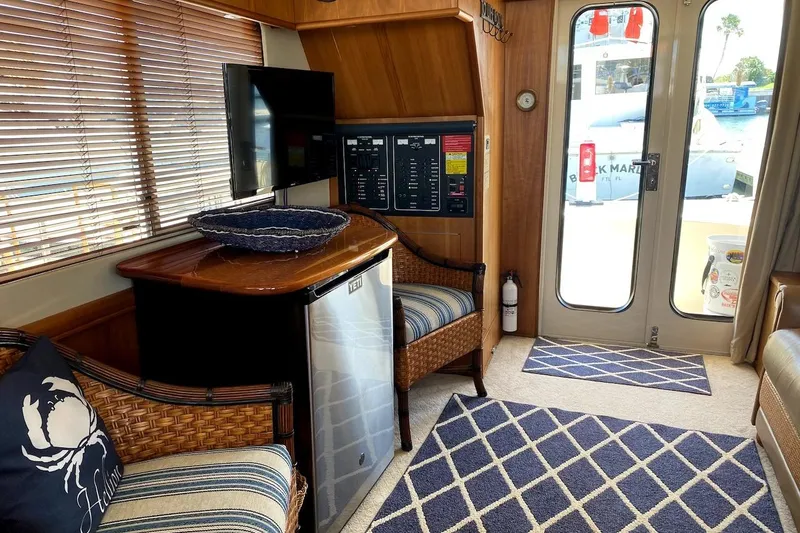 Slide: The Image of Interior of 2005 Mainship 34 Trawler with wicker chairs, TV, and nautical decor. - 15