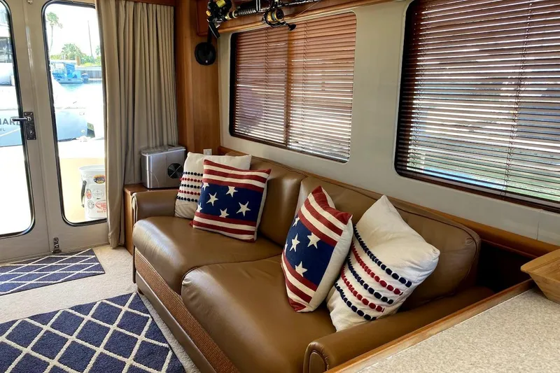 Slide: The Image of Interior of 2005 Mainship 34 Trawler with patriotic-themed pillows on a leather sofa. - 17