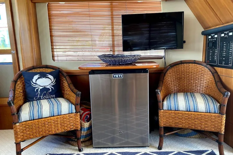 Slide: The Image of 2005 Mainship 34 Trawler interior with wicker chairs, Yeti fridge, and TV. - 19