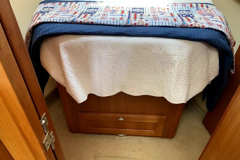 Slide: The Image of Cozy cabin bed in 2005 Mainship 34 Trawler with nautical-themed quilt. - 2
