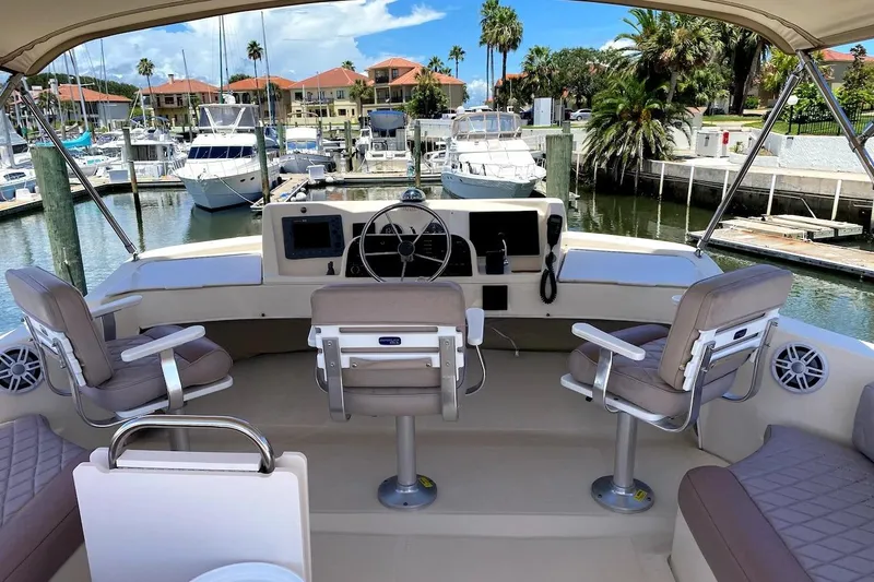 Slide: The Image of 2005 Mainship 34 Trawler helm with seating, docked in a marina with palm trees. - 25