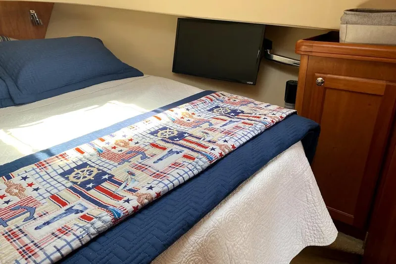 Slide: The Image of Cozy bedroom in 2005 Mainship 34 Trawler with nautical-themed bedding and wooden cabinetry. - 3