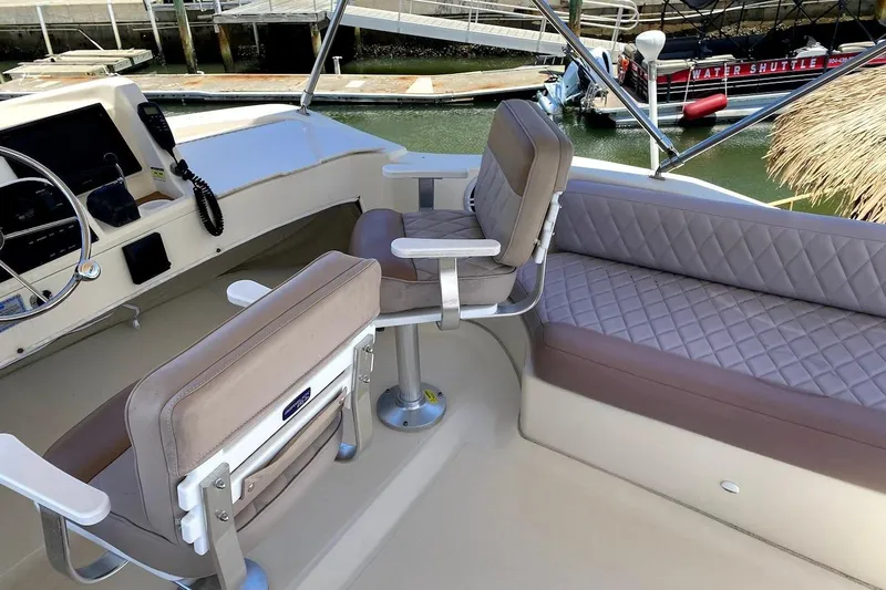 Slide: The Image of 2005 Mainship 34 Trawler interior with helm, seating, and water view. - 34