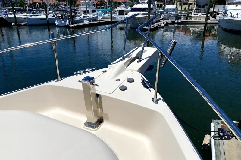 Slide: The Image of 2005 Mainship 34 Trawler bow view at marina, showcasing sleek design and stainless steel railings. - 38