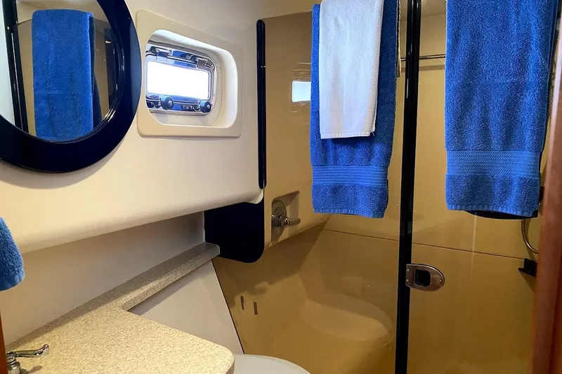 Slide: The Image of Bathroom interior of 2005 Mainship 34 Trawler with blue towels and porthole window. - 5