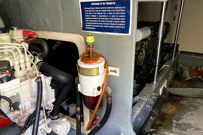 Slide: The Image of Engine room of 2005 Mainship 34 Trawler with visible fuel filter and warning sign. - 53