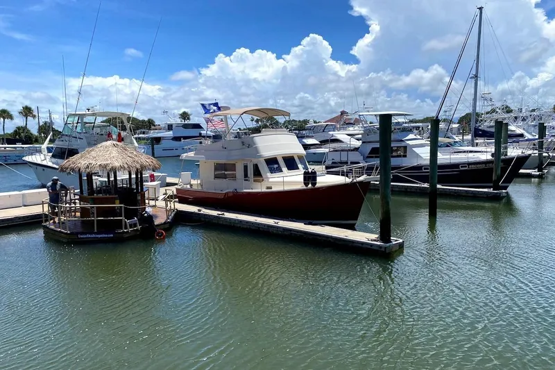 Slide: The Image of 2005 Mainship 34 Trawler docked at a marina under a clear blue sky. - 54