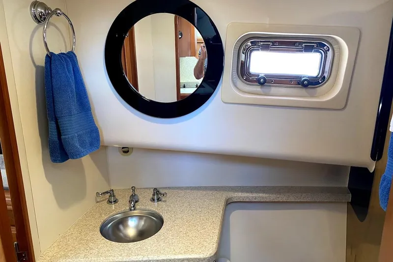 Slide: The Image of Bathroom interior of 2005 Mainship 34 Trawler with sink, mirror, and porthole window. - 7