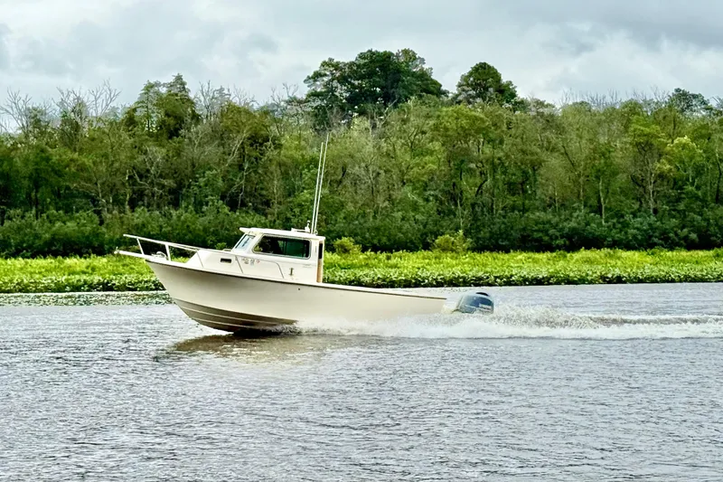 The Image of 2008 Parker 2520XLD boat cruising on a river with lush green forest backdrop. - 0