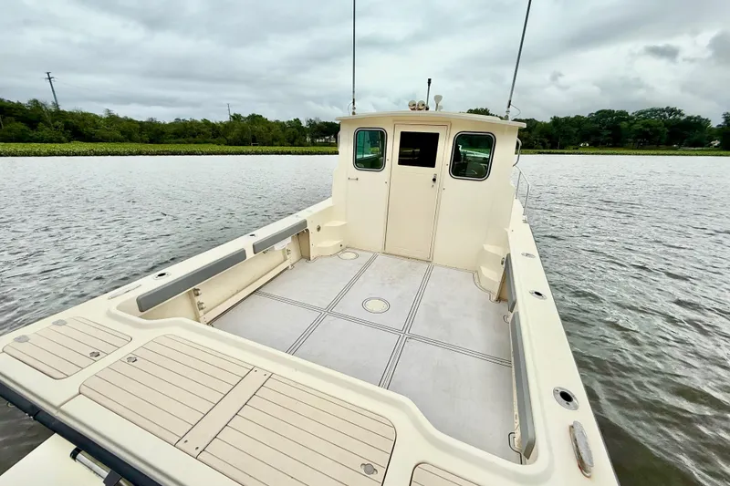Slide: The Image of 2008 Parker 2520XLD boat on calm water, spacious deck, overcast sky. - 3