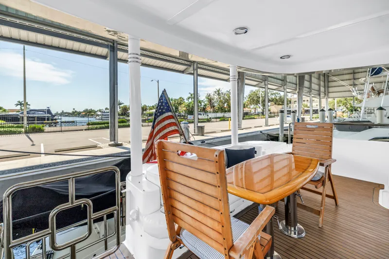 Slide: The Image of Outdoor seating on 2000 Neptunus 65 Flybridge yacht with American flag and marina view. - 18