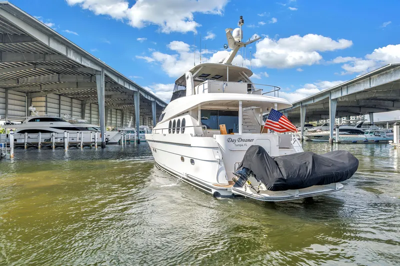 Slide: The Image of Luxury 2000 Neptunus 65 Flybridge yacht docked in marina, featuring American flag. - 4
