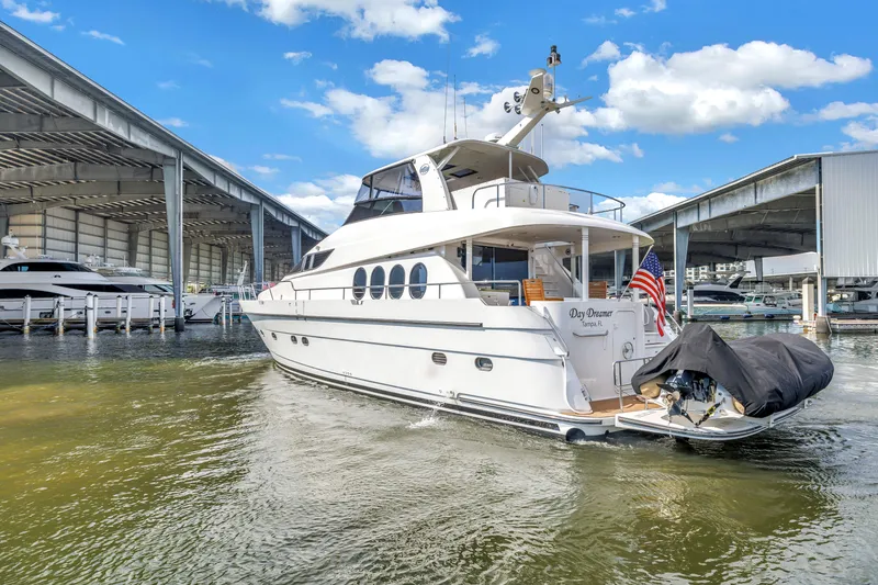 Slide: The Image of Luxury Neptunus 65 Flybridge yacht docked, 2000 model, with American flag, under blue sky. - 6
