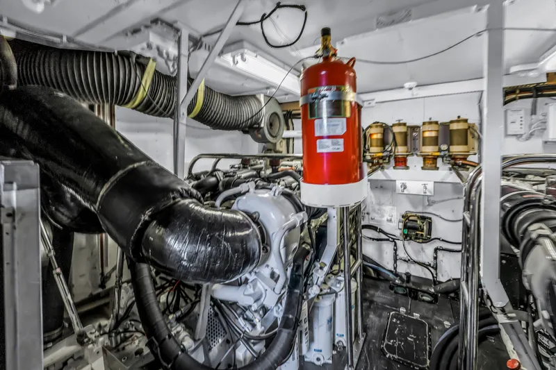 Slide: The Image of Engine room of 2000 Neptunus 65 Flybridge yacht with visible machinery and fire extinguisher. - 62