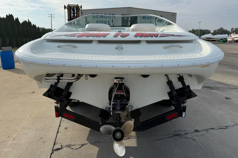 Slide: The Image of 1994 Baja Boss 272 boat rear view with "Born to Run" decal, parked on concrete. - 8