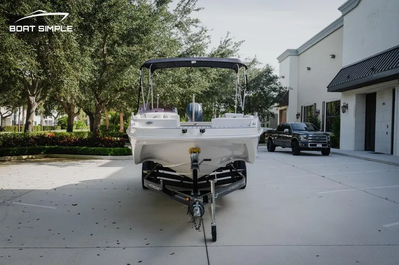 Slide: The Image of 2023 Starcraft SVX 211 OB boat on trailer in parking lot, surrounded by trees. - 2