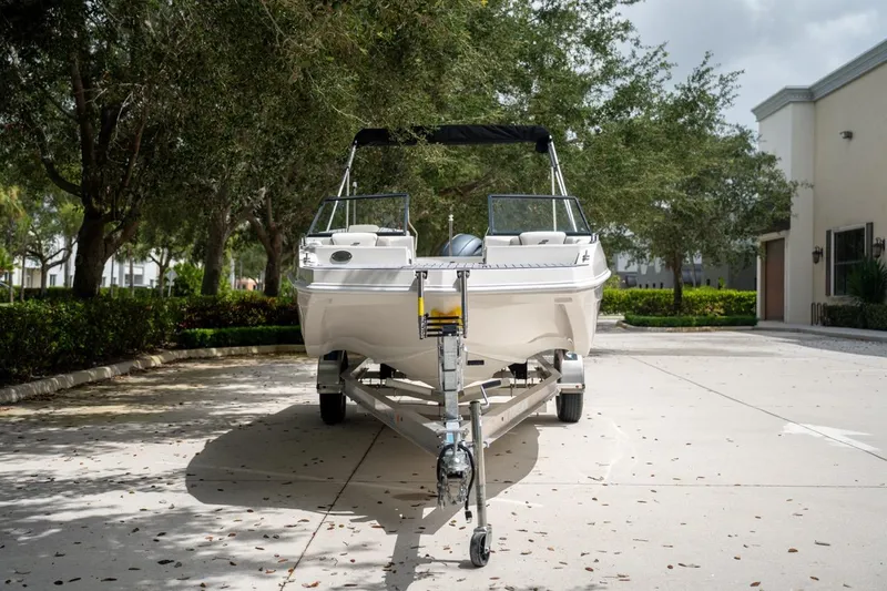 Slide: The Image of 2022 Starcraft SVX 190 DC boat on trailer, parked outdoors under trees. - 5