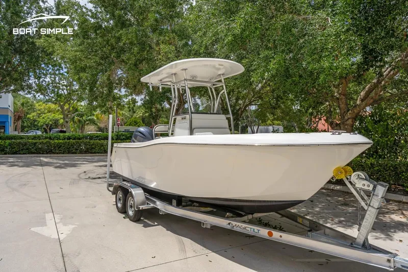 Slide: The Image of 2020 Release 210 RX boat on trailer, parked outdoors under trees. - 2