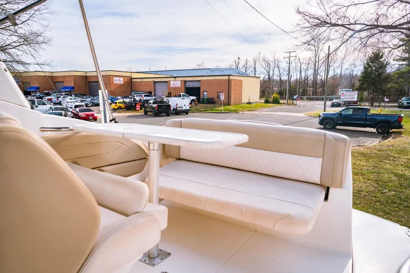 Slide: The Image of 2018 Chaparral 270 Signature boat interior with seating and table, parked near commercial buildings. - 5