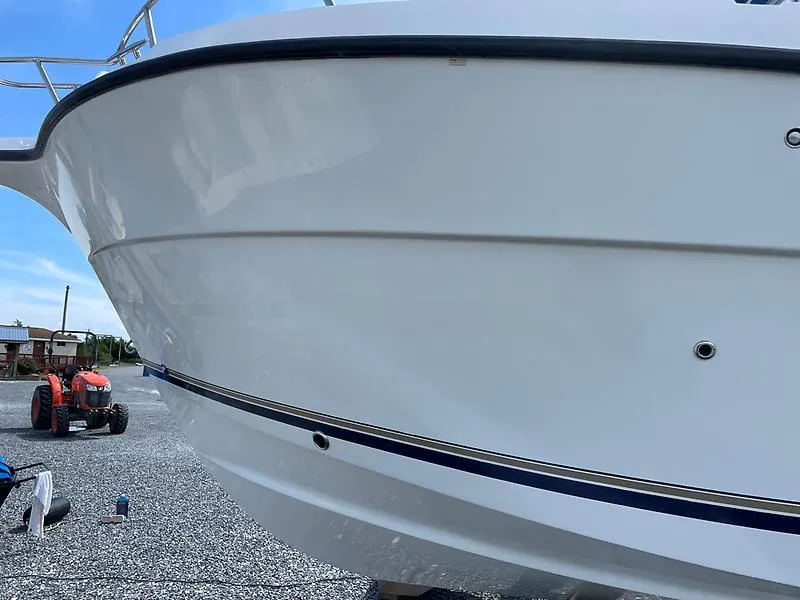 Slide: The Image of 2001 Shamrock 270 Open boat on gravel, with a tractor in the background. - 10