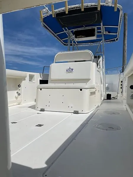 Slide: The Image of 2001 Shamrock 270 Open boat with blue canopy and spacious deck under clear sky. - 12